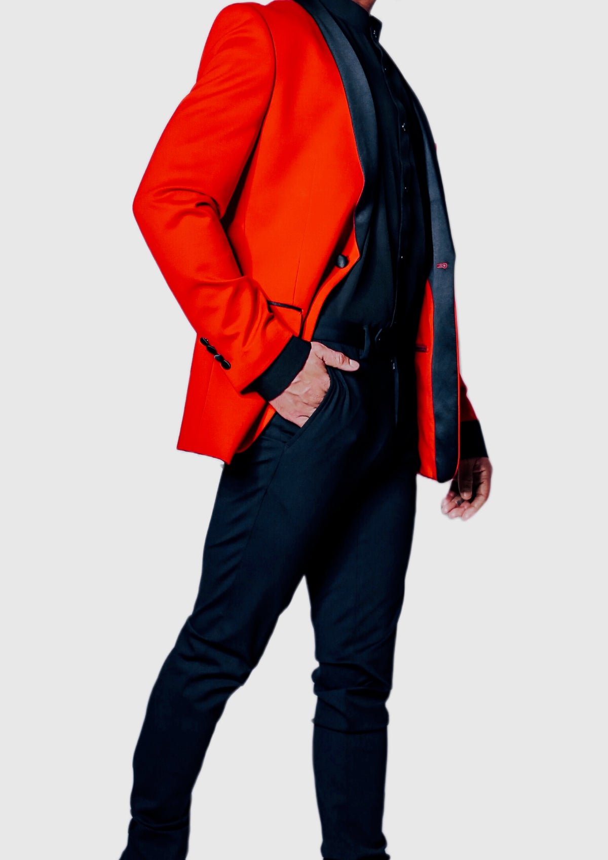 Men's Red Stretch Tuxedo Jacket on model, three-quarter view with hand in pocket and black satin shawl lapel